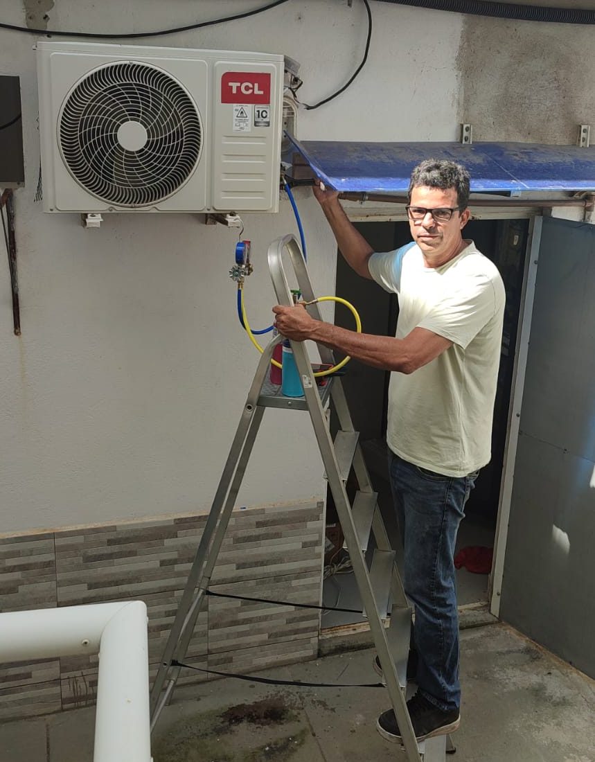 Rafael fazendo a manutenção de um ar-condicionado split, com os manômetros conectados à unidade externa