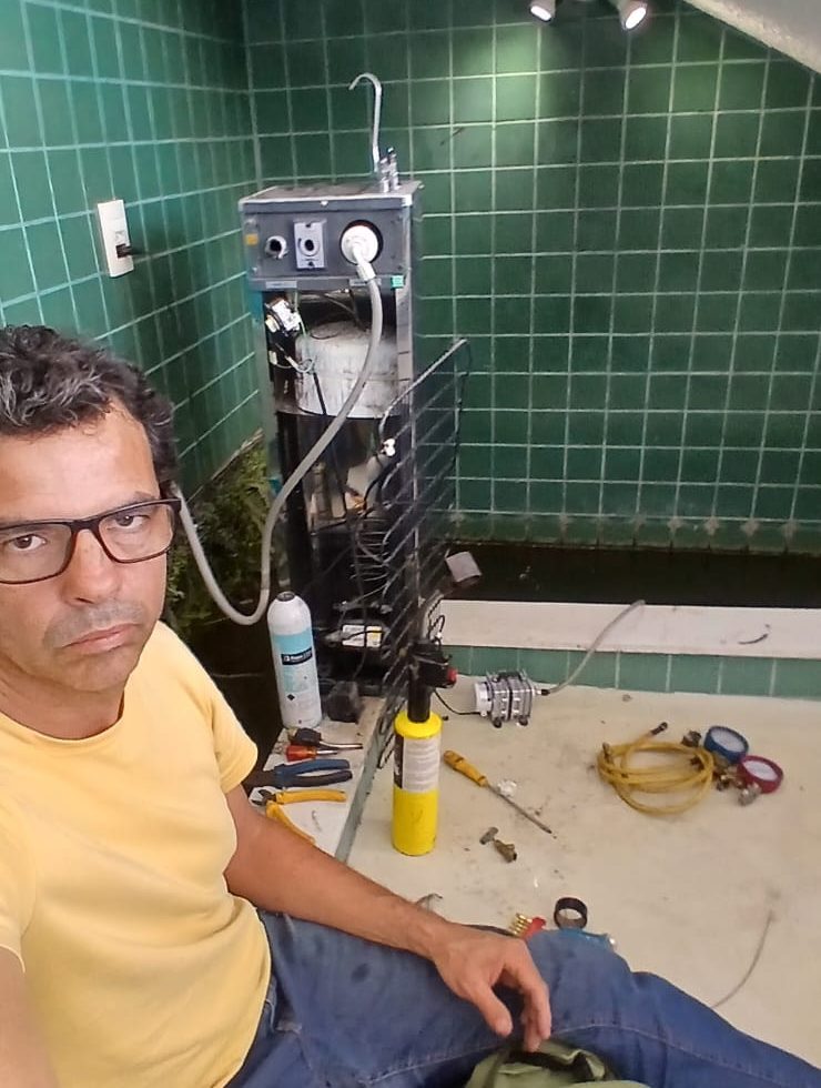 Rafael durante a manutenção de um bebedouro industrial, com o aparelho aberto e as ferramentas ao lado